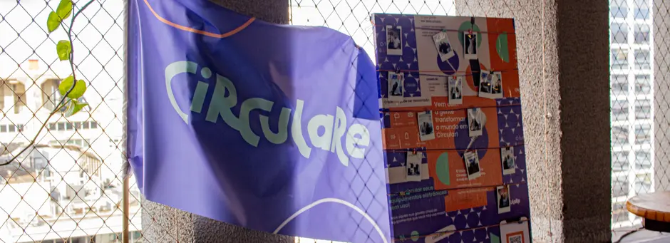 Bandeira da Circulare pendurada ao lado de um painel com fotos da equipe
