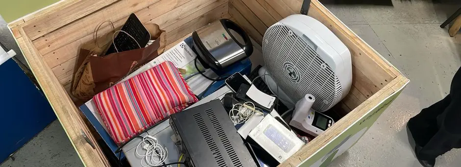Caixa de madeira com eletrônicos descartados, como ventilador, roteador e cabos
